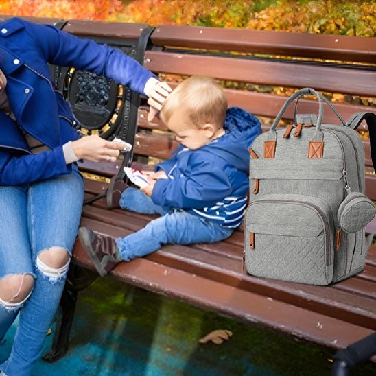 bébé sur le bans et sac à dos à langer