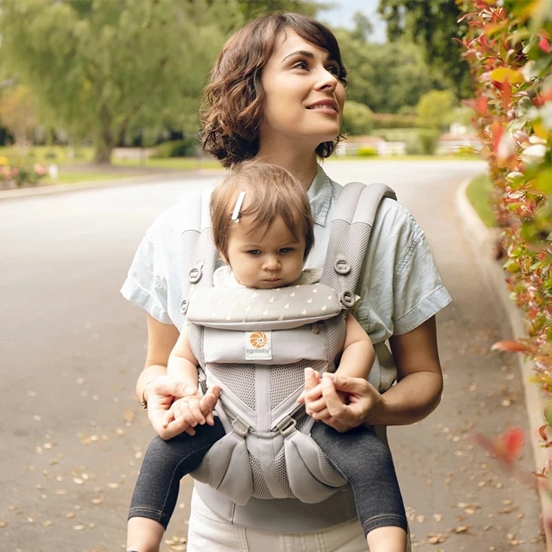 Parent portant bébé en porte bebe promenade extérieure arborée