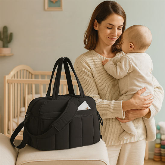 bebe dans le bras de maman et sac a langer noir
