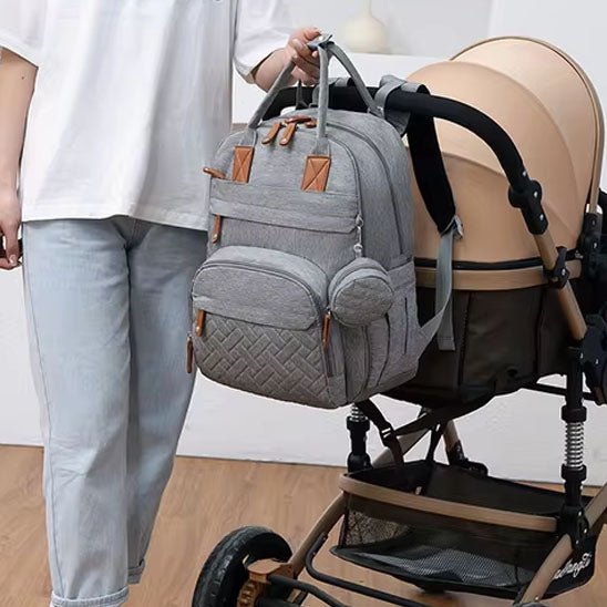 maman et sa poussette beige noir et sac à dos à langer