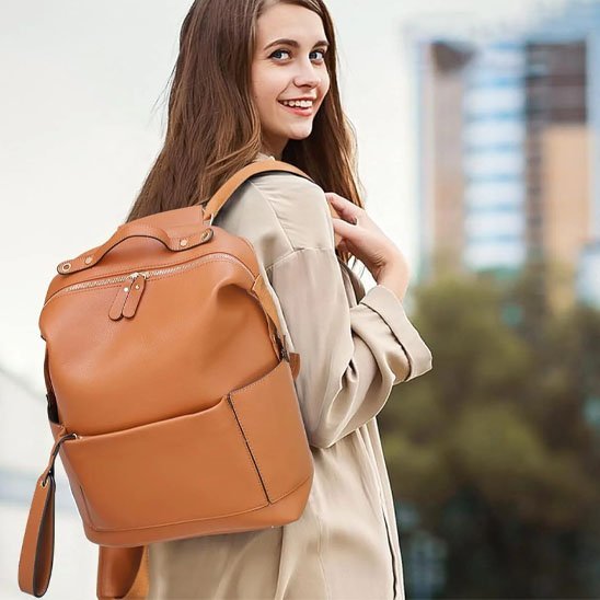 maman souriante avec son sac à dos à langer marron chemisier beige