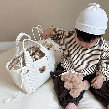 un petit garçon assis avec sac à langer